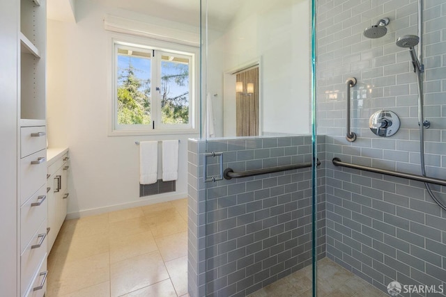bathroom featuring tile patterned floors, vanity, baseboards, and a stall shower