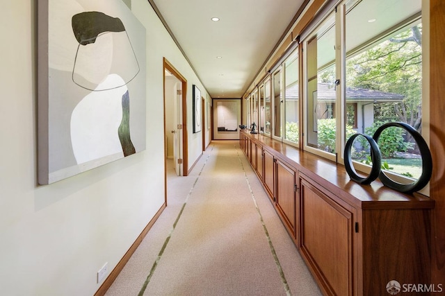 hallway featuring recessed lighting, plenty of natural light, and baseboards