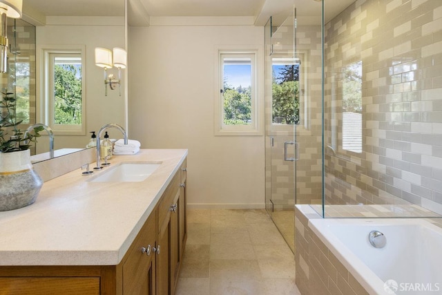 full bathroom with a shower stall, vanity, tile patterned flooring, a relaxing tiled tub, and baseboards