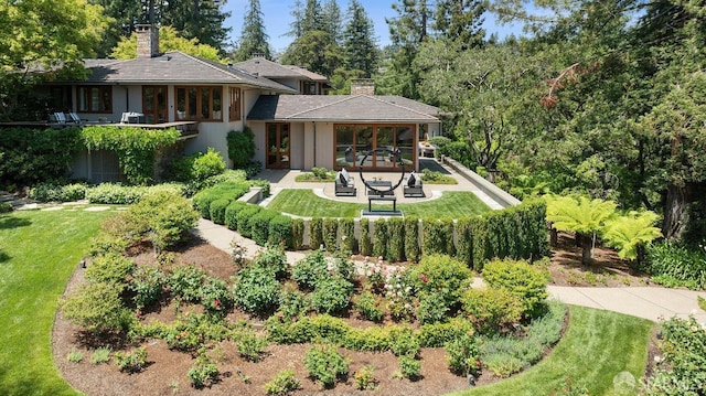 rear view of house with a patio area, stucco siding, a lawn, and a chimney