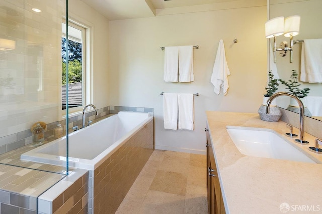 full bath featuring a bath, vanity, and baseboards