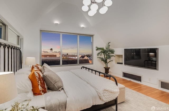 bedroom with lofted ceiling, an inviting chandelier, and light wood-type flooring