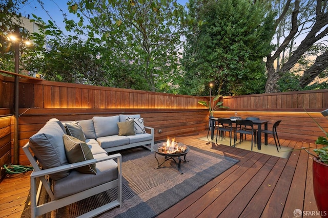 deck at dusk featuring an outdoor living space with a fire pit