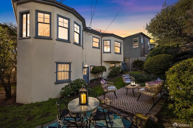 back house at dusk featuring a patio