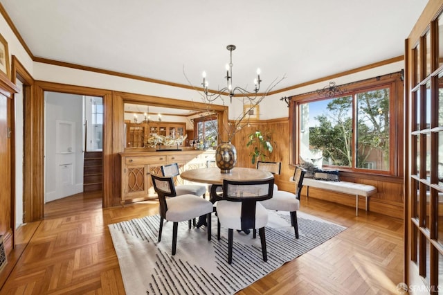 dining room featuring light parquet flooring, crown molding, a chandelier, and wooden walls