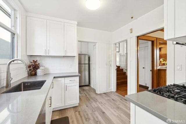 kitchen featuring white cabinets, a healthy amount of sunlight, tasteful backsplash, sink, and stainless steel fridge