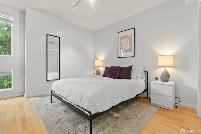 bedroom featuring wood-type flooring and track lighting