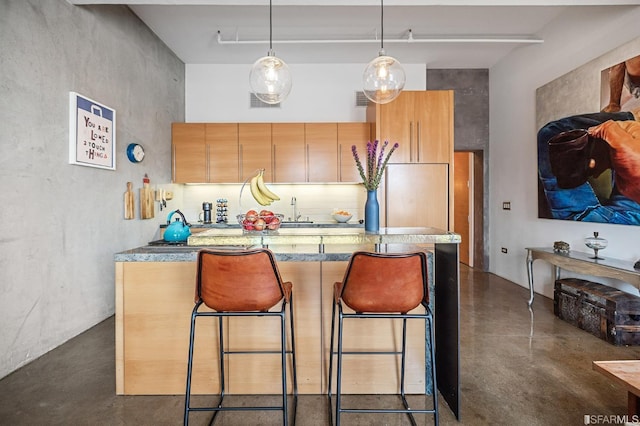 kitchen featuring sink, a kitchen bar, tasteful backsplash, a kitchen island, and decorative light fixtures