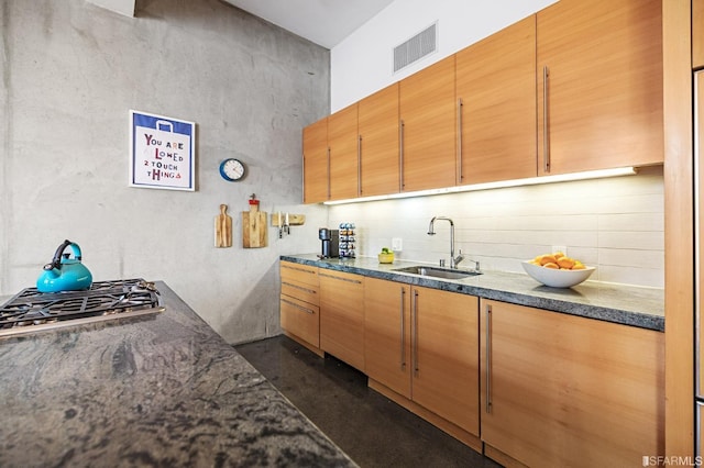 kitchen featuring stainless steel gas stovetop, tasteful backsplash, and sink