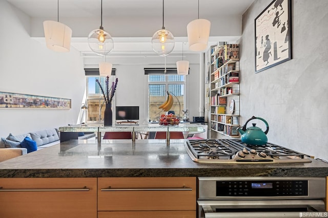 kitchen with stainless steel appliances, pendant lighting, and dark stone counters