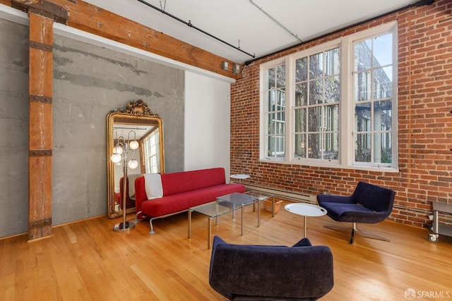 living area featuring brick wall, a baseboard radiator, and hardwood / wood-style flooring