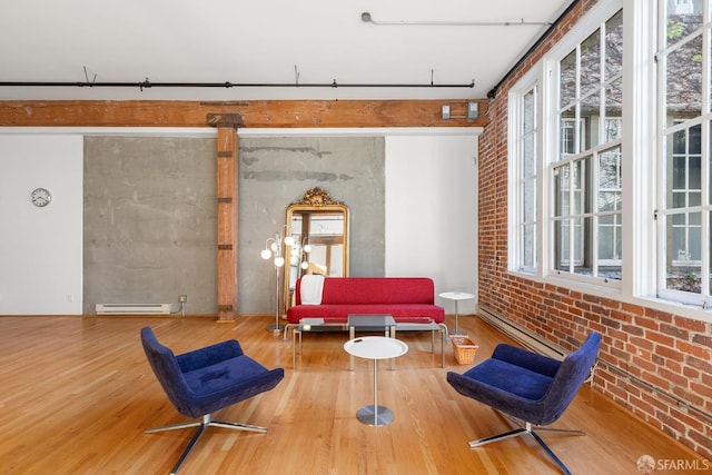 living area featuring hardwood / wood-style flooring, plenty of natural light, brick wall, and a baseboard radiator