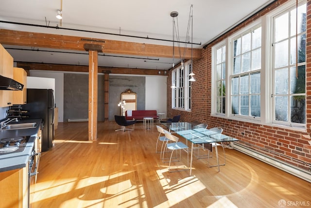 interior space featuring light hardwood / wood-style floors, baseboard heating, sink, and brick wall