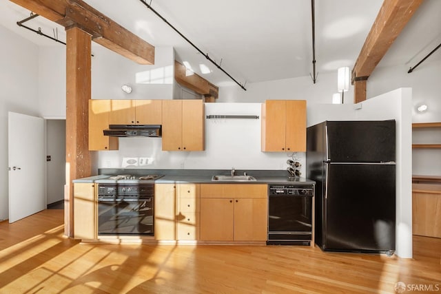 kitchen featuring light brown cabinetry, a towering ceiling, sink, black appliances, and beamed ceiling