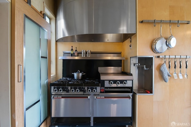 kitchen featuring high end stove, refrigerator, and wall chimney exhaust hood