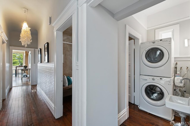 washroom with dark hardwood / wood-style floors, stacked washer / drying machine, and sink