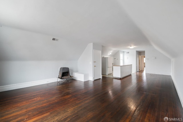 bonus room with lofted ceiling, a wood stove, and dark wood-type flooring