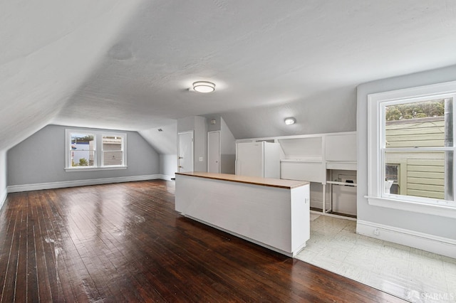 bonus room with dark hardwood / wood-style flooring, lofted ceiling, and a textured ceiling