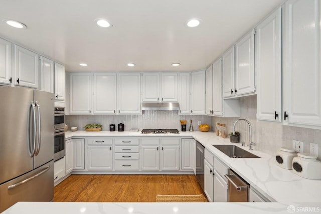 302 Warren Dr, San Francisco, CA 94131 - kitchen with appliances with stainless steel finishes, white cabinetry, light wood-style flooring, tasteful backsplash, and under cabinet range hood