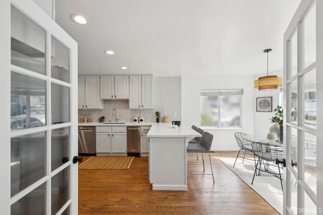 302 Warren Dr, San Francisco, CA 94131 - kitchen with dishwasher, a peninsula, a breakfast bar area, wood finished floors, and recessed lighting