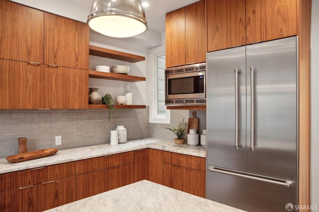 kitchen with tasteful backsplash, built in appliances, and light stone countertops