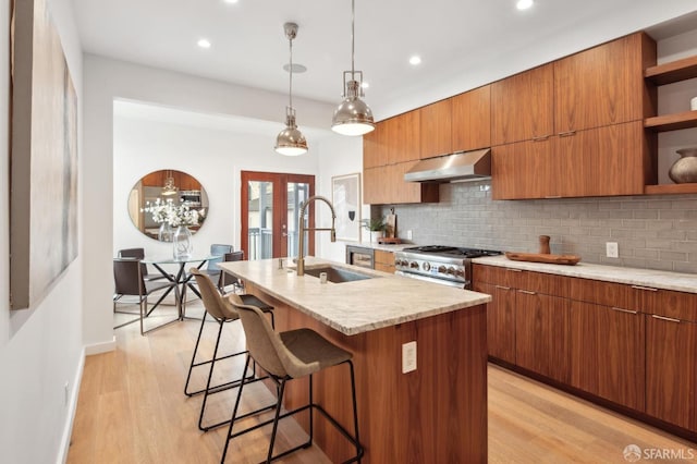 kitchen featuring pendant lighting, sink, high end stainless steel range oven, a center island with sink, and french doors