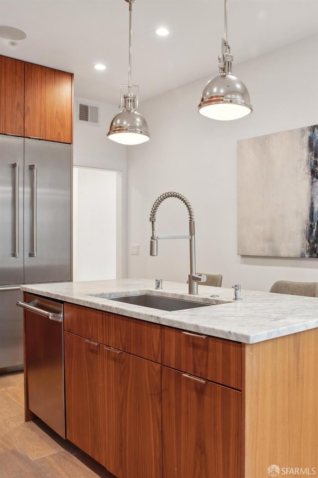 kitchen with sink, decorative light fixtures, stainless steel appliances, and light stone countertops