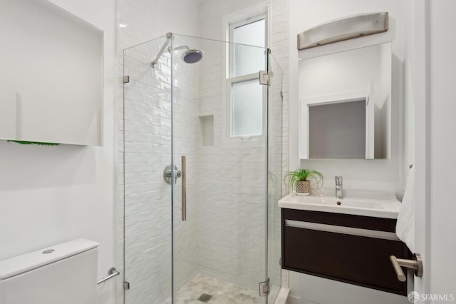 bathroom featuring vanity, toilet, and a shower with shower door