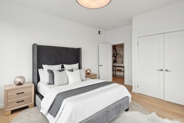 bedroom with light hardwood / wood-style floors and a closet