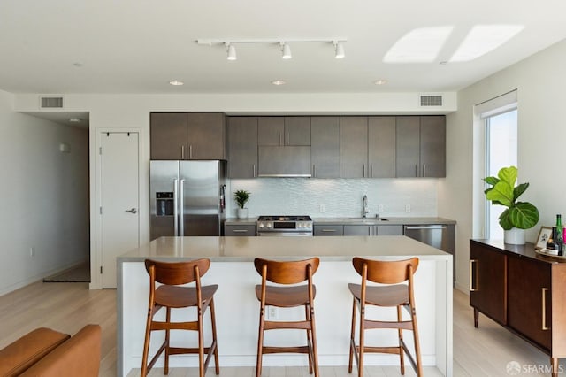 kitchen with a kitchen island, a kitchen bar, sink, and appliances with stainless steel finishes