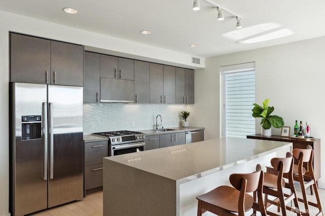 kitchen with a center island, backsplash, a kitchen breakfast bar, sink, and stainless steel appliances