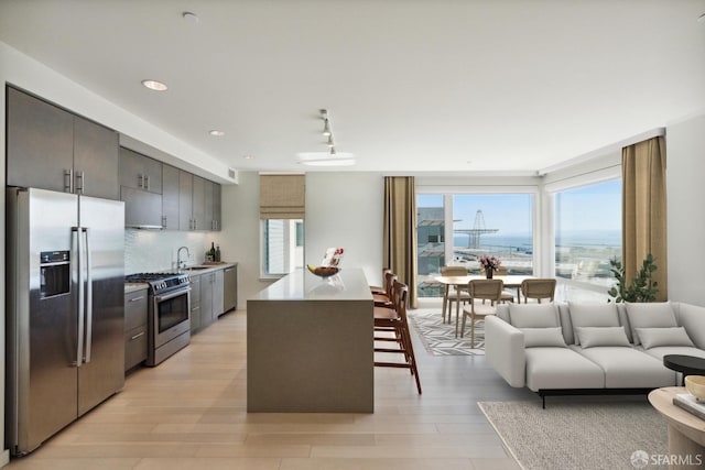 kitchen with sink, backsplash, track lighting, a kitchen bar, and appliances with stainless steel finishes