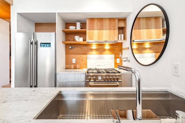 kitchen with high end appliances, light stone countertops, backsplash, and extractor fan