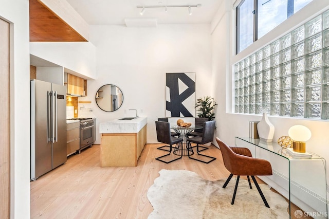 home office with sink, rail lighting, and light wood-type flooring