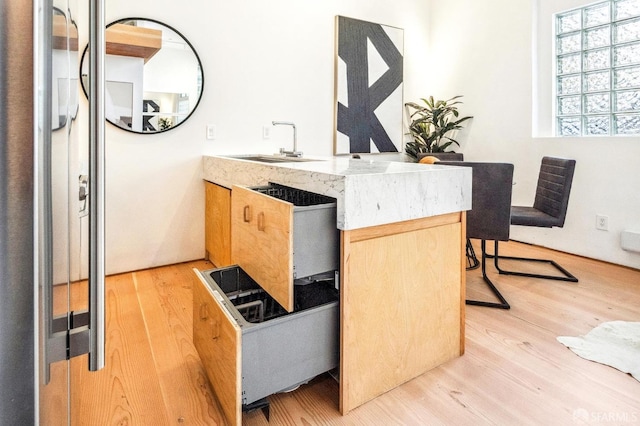 bar with light brown cabinets, sink, and light wood-type flooring