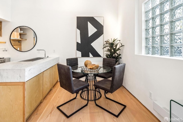 dining room with sink, light hardwood / wood-style flooring, and a healthy amount of sunlight