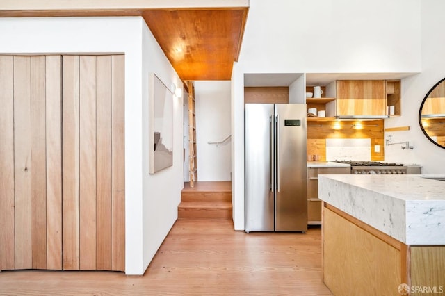 kitchen with backsplash, ventilation hood, appliances with stainless steel finishes, and light hardwood / wood-style floors