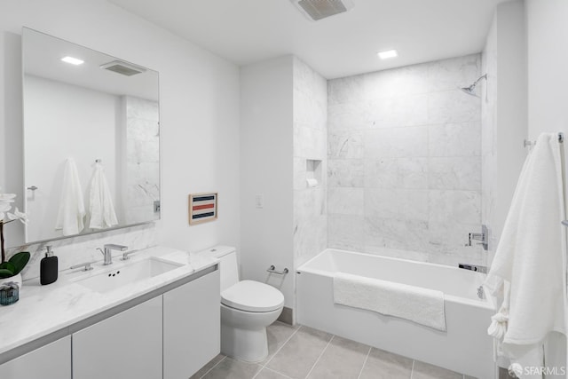 full bathroom featuring tile patterned flooring, tiled shower / bath combo, vanity, and toilet