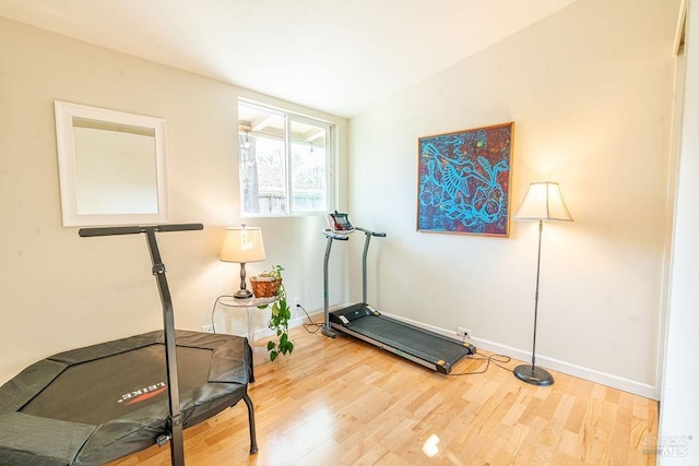 exercise area with vaulted ceiling, wood finished floors, and baseboards