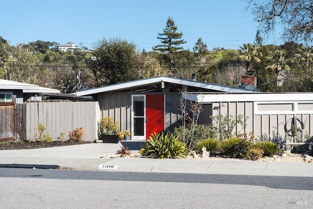 mid-century modern home with fence and board and batten siding