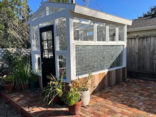 view of home's exterior with an outbuilding, a shingled roof, and fence