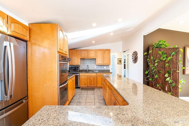 kitchen featuring a sink, light stone counters, tasteful backsplash, appliances with stainless steel finishes, and light tile patterned flooring