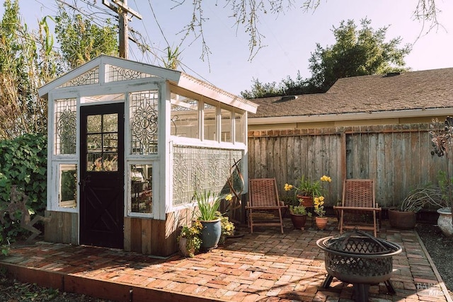 view of outbuilding with an outdoor fire pit, an outdoor structure, and fence