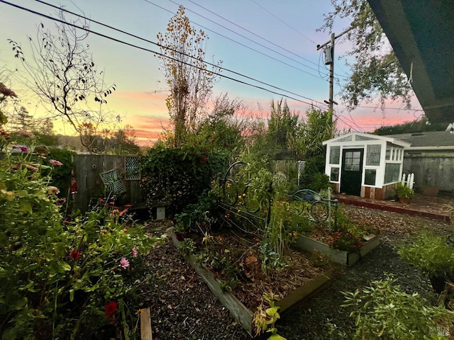 view of yard with an outbuilding, a vegetable garden, a greenhouse, and fence