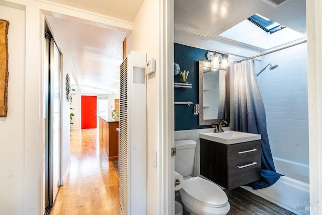 bathroom with a skylight, wainscoting, toilet, and wood finished floors