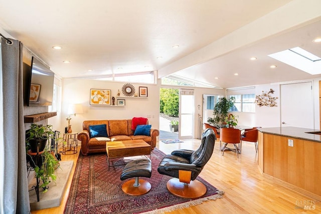 living room with recessed lighting, vaulted ceiling with skylight, and light wood-style flooring