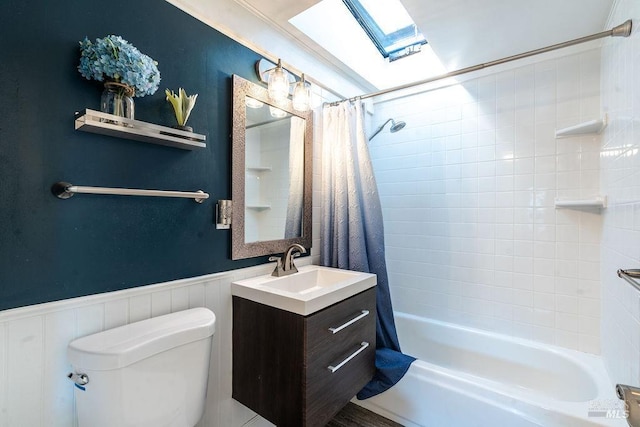 full bath with toilet, shower / bath combo, a skylight, wainscoting, and vanity