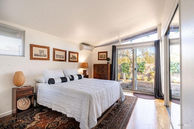 bedroom with access to exterior, an AC wall unit, light wood-style floors, and vaulted ceiling