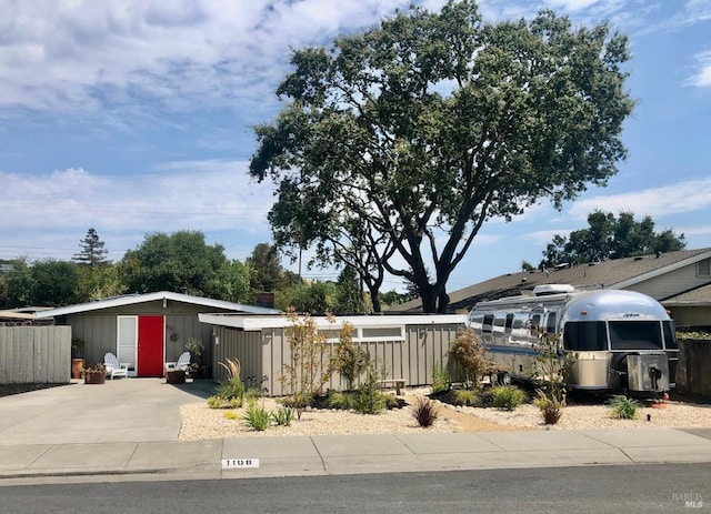 view of front facade featuring a detached carport, fence, and driveway