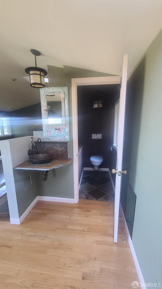 bathroom with sink, vaulted ceiling, hardwood / wood-style flooring, and toilet